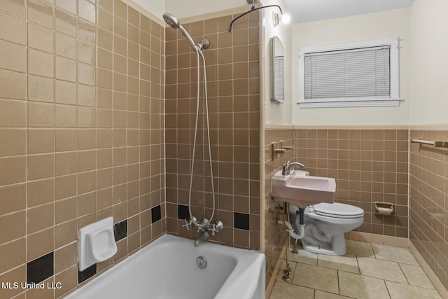 bathroom featuring tiled shower / bath combo, tile walls, tile patterned floors, and toilet