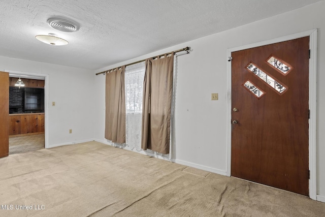 foyer entrance with carpet flooring and a textured ceiling