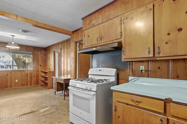 kitchen with white range with gas cooktop, pendant lighting, a textured ceiling, and wood walls