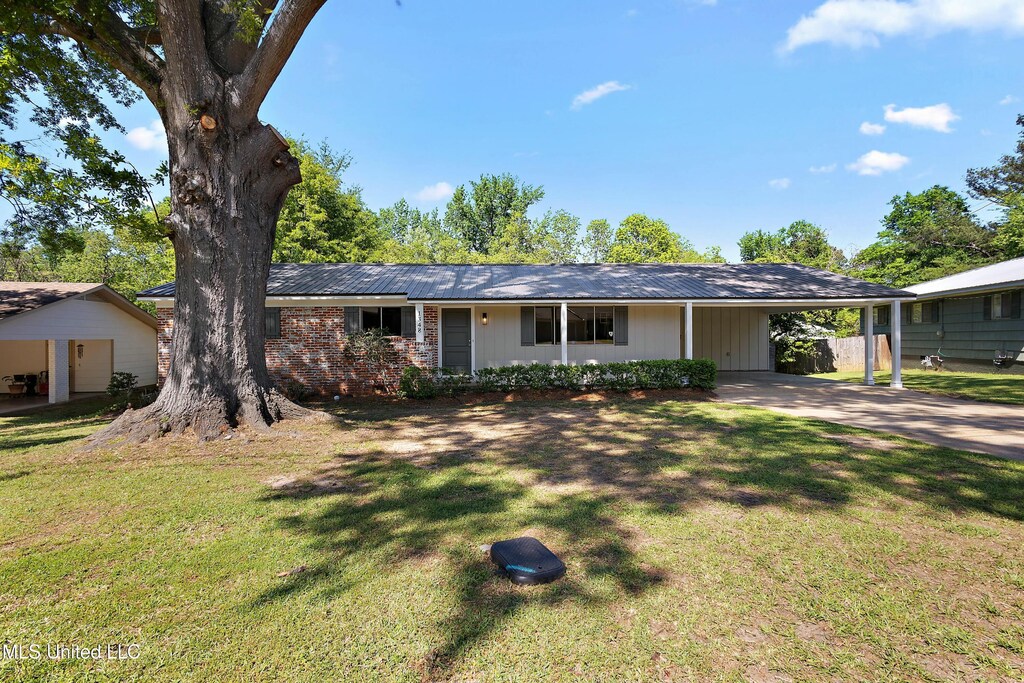 ranch-style house featuring concrete driveway, a front yard, brick siding, and a carport