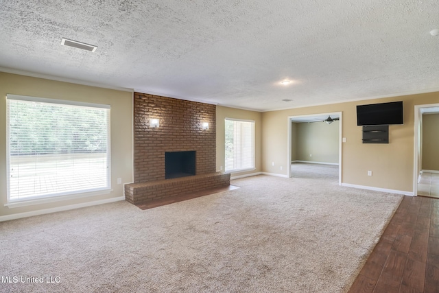 12 Bayou View Dr, Gulfport, MS 39507 - unfurnished living room with a textured ceiling, a brick fireplace, hardwood / wood-style floors, and ceiling fan