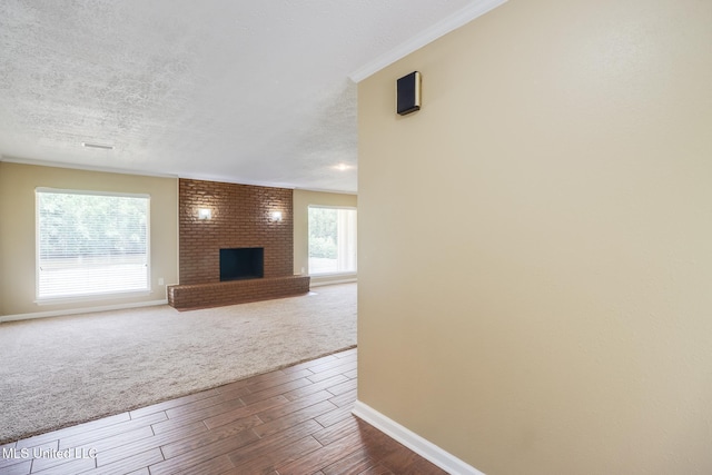 12 Bayou View Dr, Gulfport, MS 39507 - unfurnished living room featuring dark wood-type flooring, a brick fireplace, a textured ceiling, and dark colored carpet