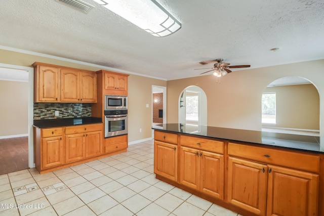 12 Bayou View Dr, Gulfport, MS 39507 - kitchen featuring appliances with stainless steel finishes, dark countertops, arched walkways, a textured ceiling, and ornamental molding