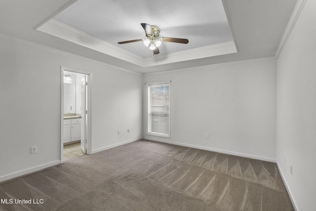 unfurnished bedroom featuring carpet floors, baseboards, a tray ceiling, and crown molding