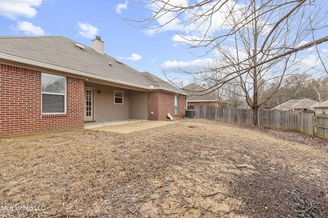 back of property with a chimney, brick siding, a patio, and a fenced backyard