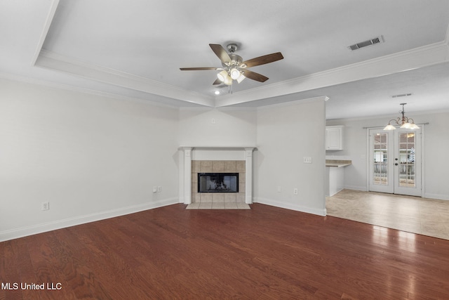 unfurnished living room with a tile fireplace, a raised ceiling, visible vents, and wood finished floors