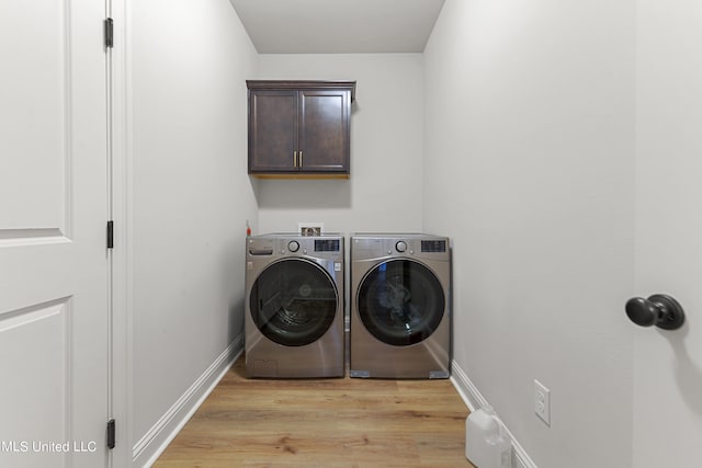 clothes washing area featuring light hardwood / wood-style flooring, separate washer and dryer, and cabinets