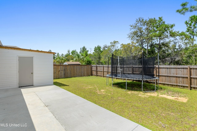 view of yard featuring a trampoline, a shed, and a patio