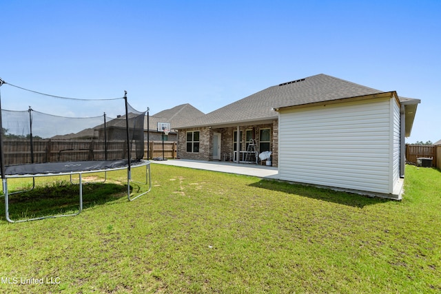 back of house featuring a patio area, a yard, and a trampoline