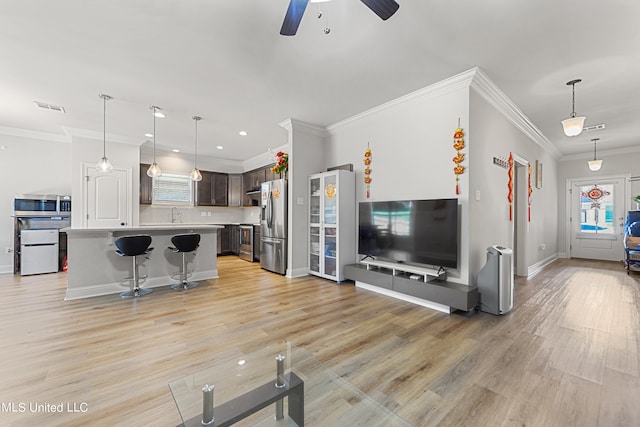 living room with crown molding, a wealth of natural light, light wood-type flooring, and ceiling fan