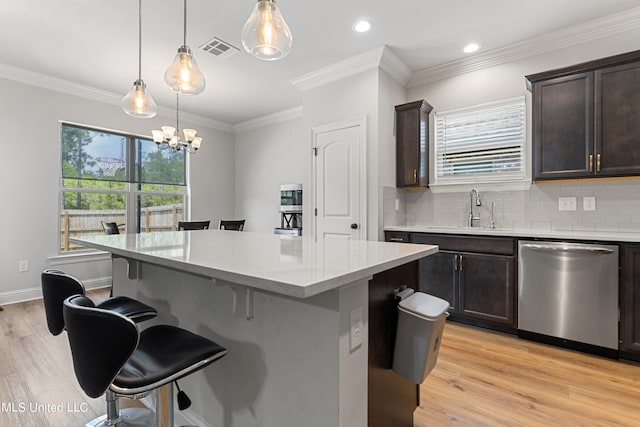 kitchen featuring dishwasher, ornamental molding, light hardwood / wood-style floors, decorative light fixtures, and a center island