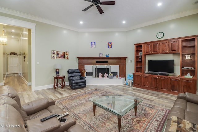 41 C G Evans Rd, Wiggins, MS 39577 - living room featuring light wood-type flooring, baseboards, a fireplace with raised hearth, a ceiling fan, and crown molding