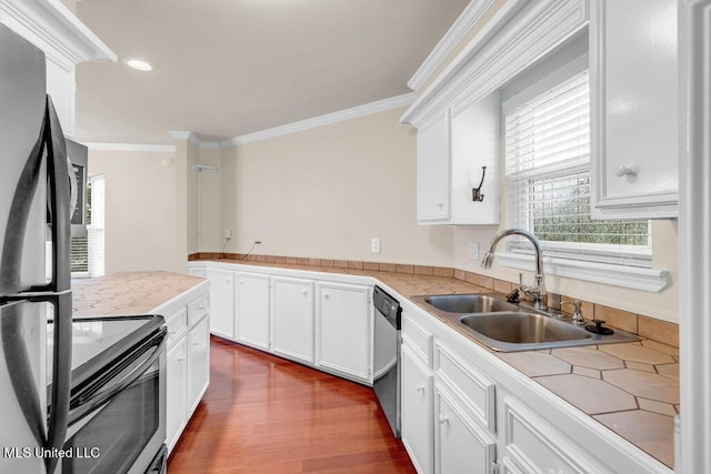kitchen featuring appliances with stainless steel finishes, crown molding, plenty of natural light, a sink, and white cabinetry