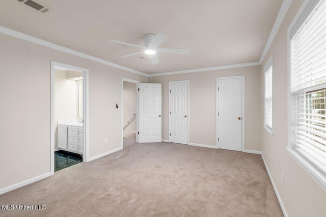 unfurnished bedroom with carpet floors, crown molding, baseboards, ensuite bathroom, and a ceiling fan