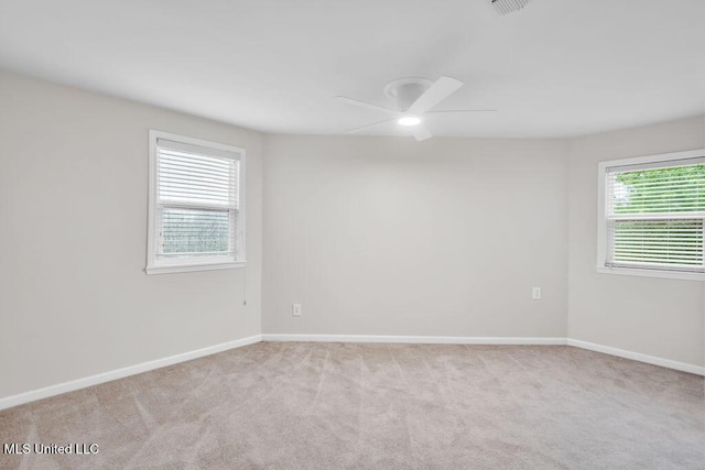 empty room featuring a ceiling fan, light carpet, and baseboards