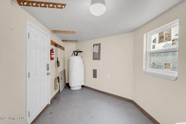 basement with baseboards, electric panel, and water heater