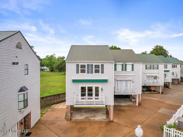 rear view of property with metal roof, fence, french doors, and a patio