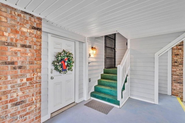 view of exterior entry with brick siding and a porch