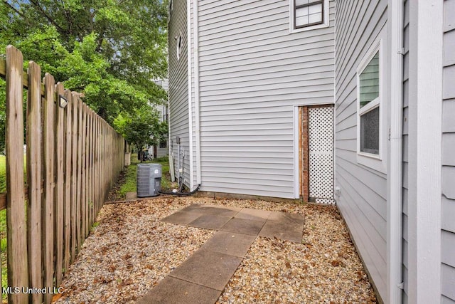 view of exterior entry featuring cooling unit and fence