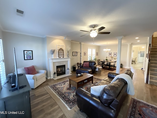 living room with hardwood / wood-style flooring, ornamental molding, ceiling fan with notable chandelier, and a fireplace