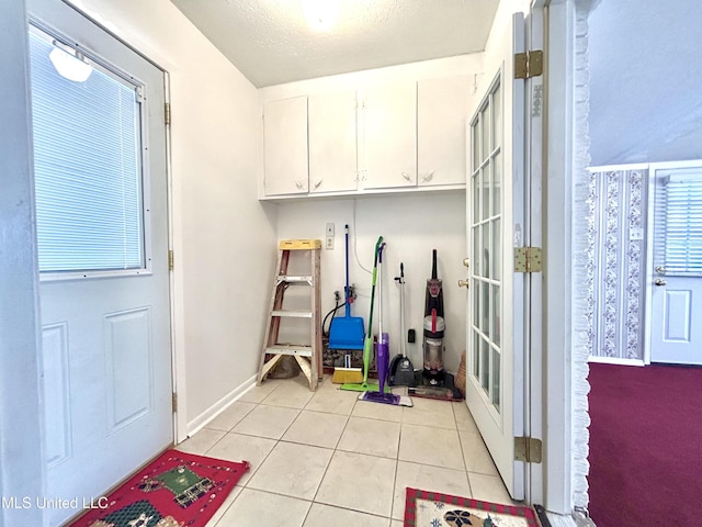 mudroom featuring light tile patterned floors, baseboards, and a textured ceiling