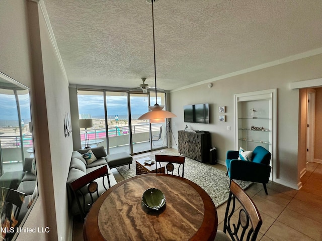 dining area featuring ceiling fan, a textured ceiling, ornamental molding, a wall of windows, and tile patterned flooring