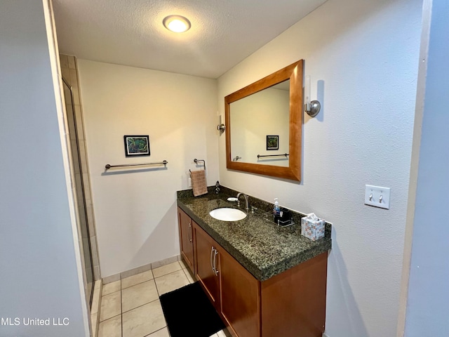 bathroom with vanity, tile patterned flooring, a textured ceiling, and walk in shower