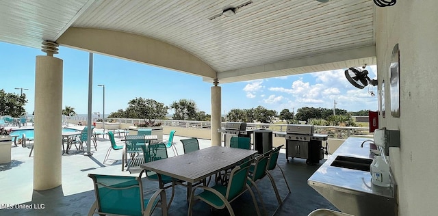 view of patio with sink, a community pool, and grilling area