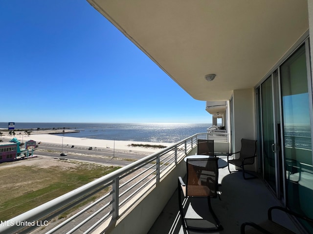 balcony with a water view and a view of the beach