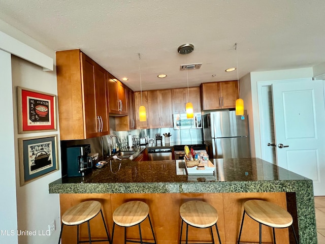 kitchen featuring hanging light fixtures, sink, a breakfast bar, light tile patterned floors, and appliances with stainless steel finishes