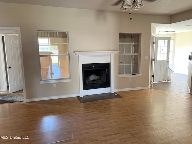 unfurnished living room with a wealth of natural light, wood-type flooring, and ceiling fan