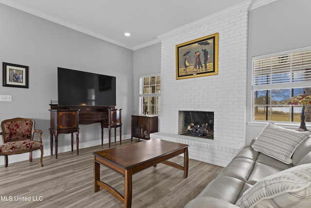 living room featuring crown molding, a fireplace, light wood-style flooring, and baseboards