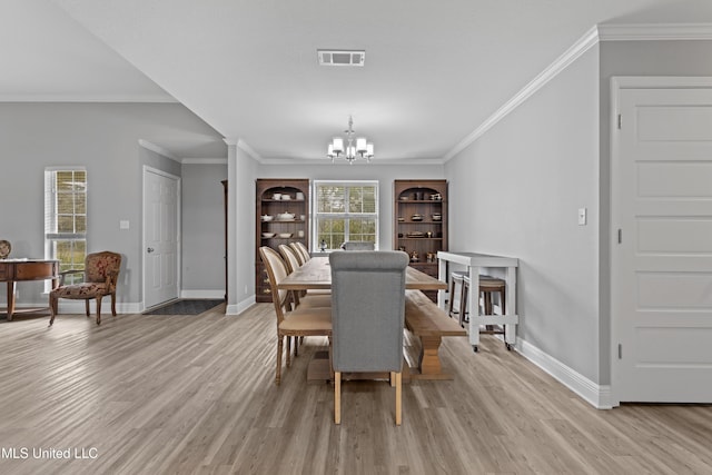 dining area with a chandelier, a wealth of natural light, light wood finished floors, and visible vents