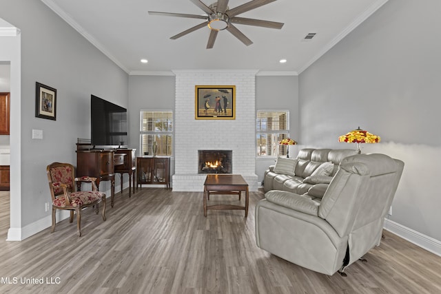 living area featuring ornamental molding, a brick fireplace, visible vents, and wood finished floors