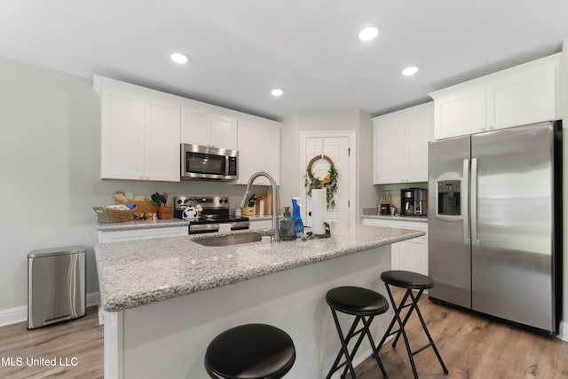 14172 Debra Barbee Ct, Gulfport, MS 39503 - kitchen with appliances with stainless steel finishes, a sink, light wood-style flooring, white cabinetry, and a kitchen bar