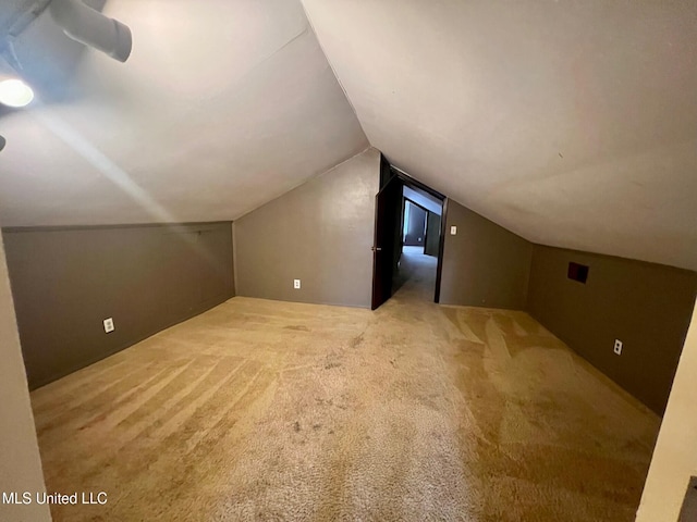 additional living space featuring lofted ceiling and light carpet