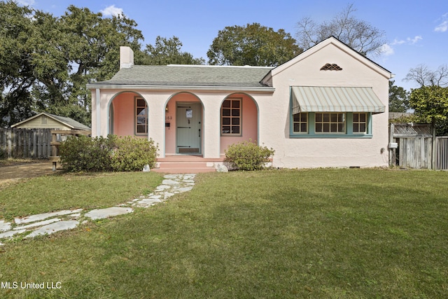 view of front of house with a porch, a front yard, fence, and stucco siding