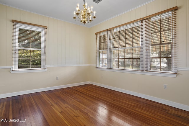 empty room with baseboards, wood-type flooring, visible vents, and an inviting chandelier