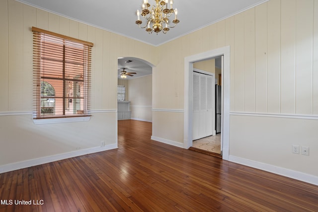 spare room featuring arched walkways, ceiling fan with notable chandelier, baseboards, wood-type flooring, and crown molding