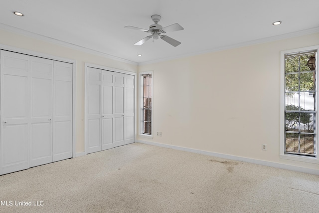 unfurnished bedroom with ornamental molding, carpet flooring, two closets, and baseboards