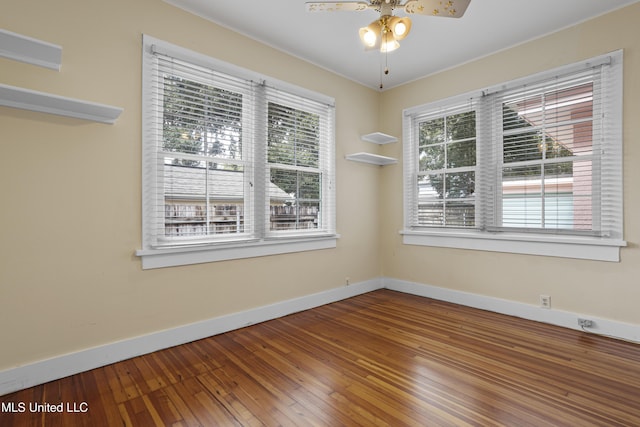 spare room featuring hardwood / wood-style flooring, a ceiling fan, baseboards, and a wealth of natural light