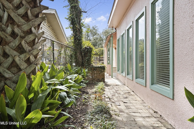 view of side of property with fence and stucco siding