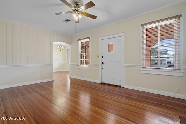 entryway featuring ceiling fan with notable chandelier, visible vents, baseboards, ornamental molding, and hardwood / wood-style floors