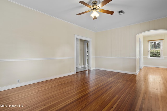 empty room featuring arched walkways, wood-type flooring, visible vents, and a ceiling fan