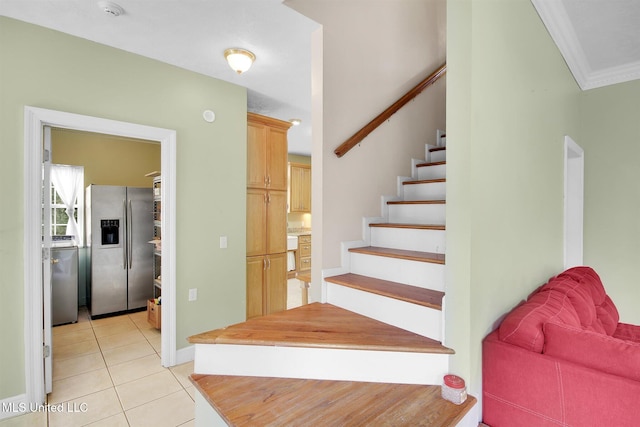 stairway with tile patterned flooring and crown molding