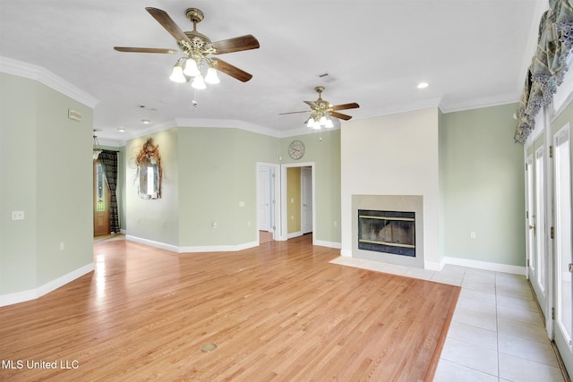 unfurnished living room with a tile fireplace, light wood-type flooring, ceiling fan, and ornamental molding