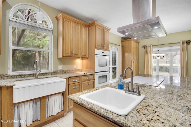 kitchen featuring sink, a notable chandelier, double oven, decorative light fixtures, and island range hood