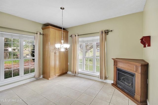 unfurnished dining area with a wealth of natural light, light tile patterned floors, and an inviting chandelier