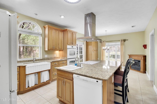 kitchen with island exhaust hood, an island with sink, a healthy amount of sunlight, and white appliances