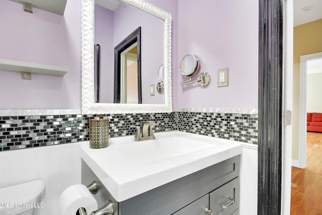 bathroom with hardwood / wood-style flooring, vanity, toilet, and backsplash